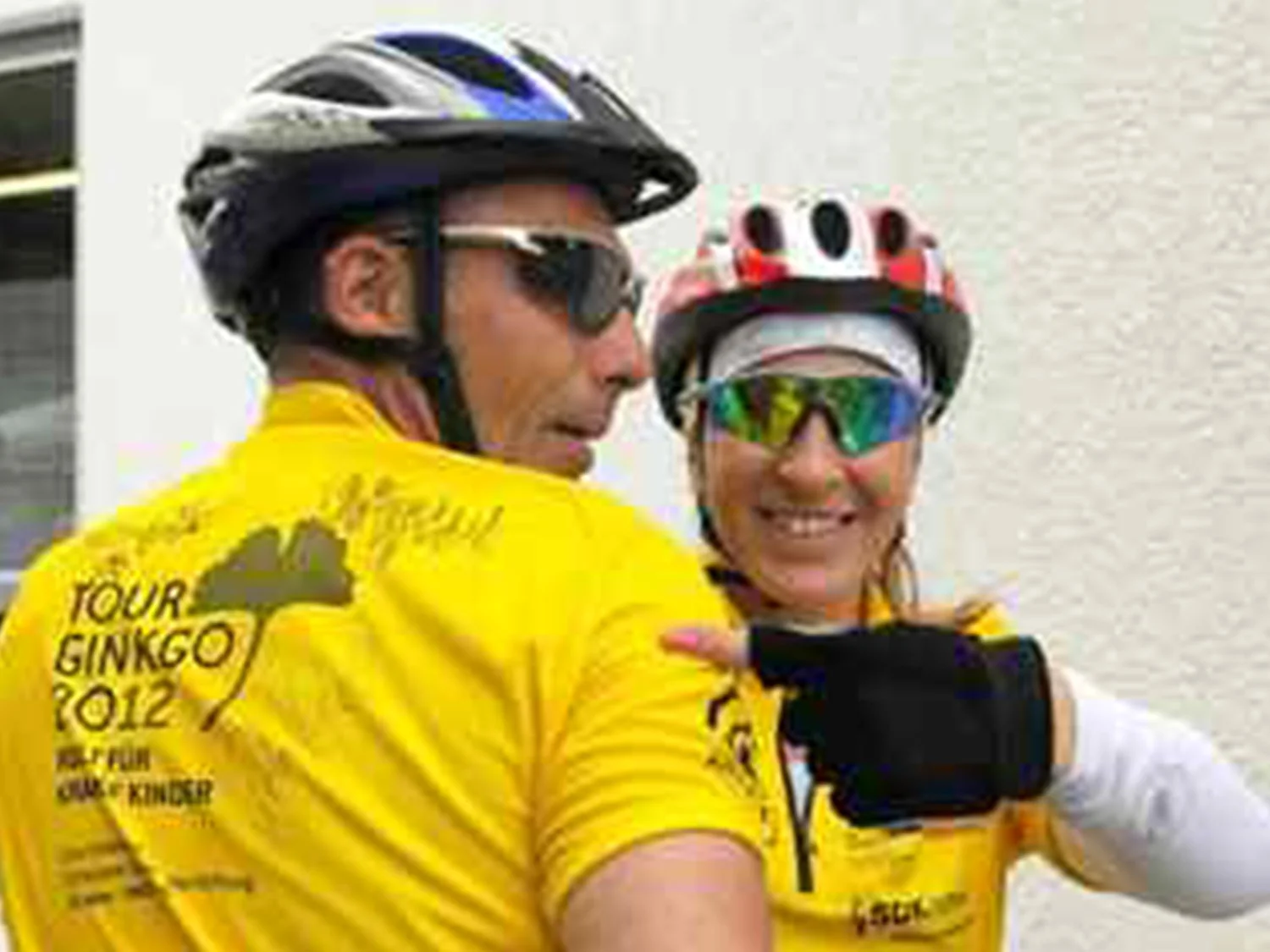 Zwei Personen in gelben T-Shirts, mit Fahrradhelm und Brille.