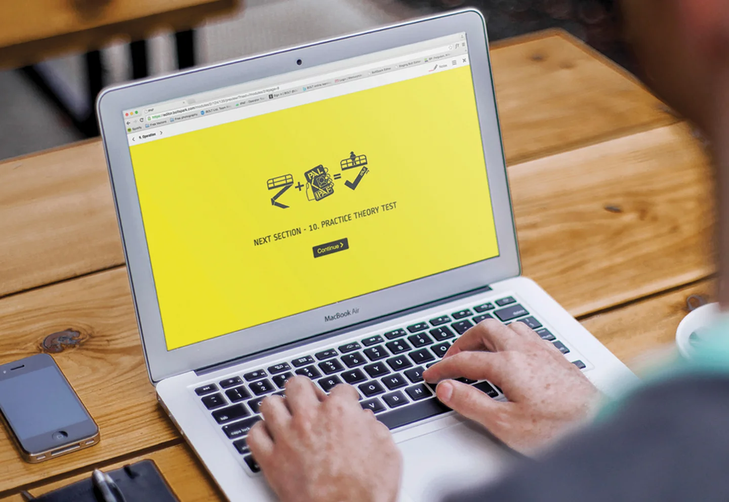 Rückansicht eines Mannes, der auf einem Holztisch am Laptop tippt.