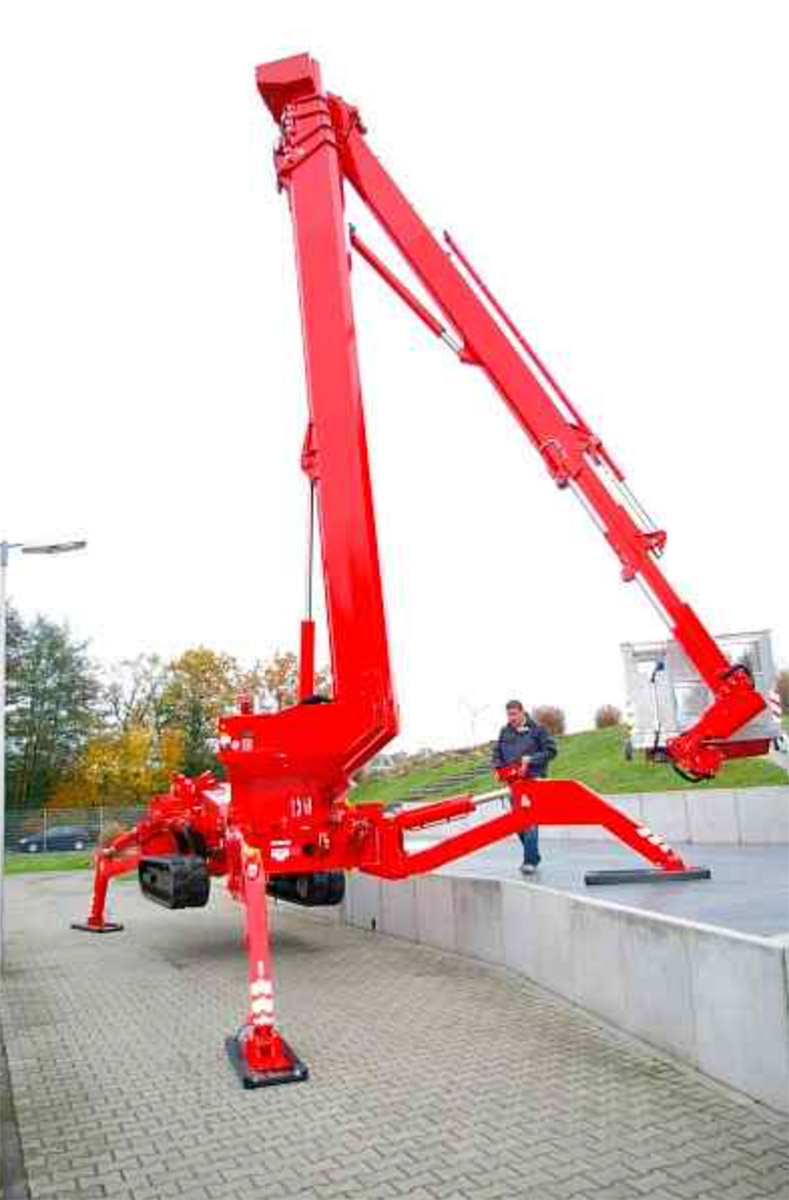 Rote Arbeitsbühne, dahinter Person und Bäume, in der Ferne Wiese und Gebäude